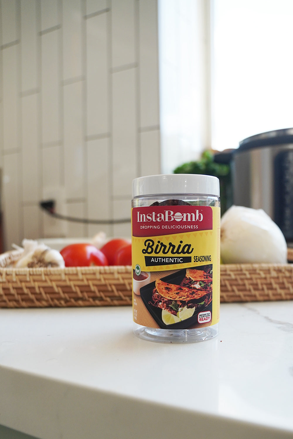 Jar of Birria seasoning on a kitchen counter, with vegetables in the background.