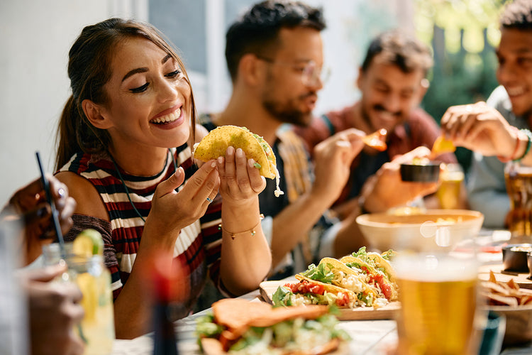 Group of friends enjoying tacos at a lively outdoor meal.